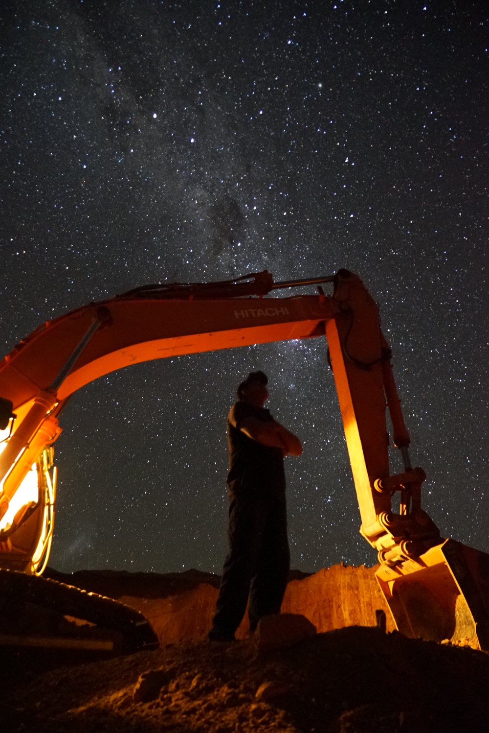 Dan beneath an excavator with the Milky Way overhead.