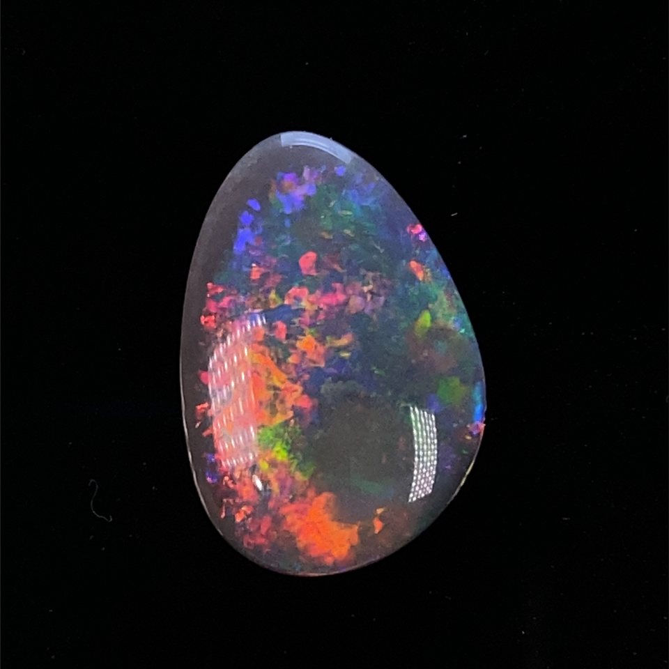 A dark-base Coober Pedy opal flashing across the spectrum.