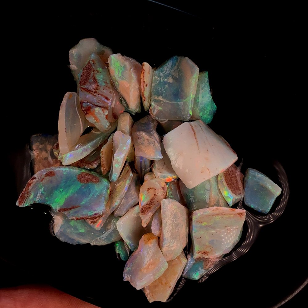 Wet rough crystal opal chips flashing green and red.