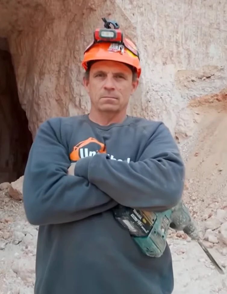 Dan standing at a mine entrance with a rotary hammer drill.