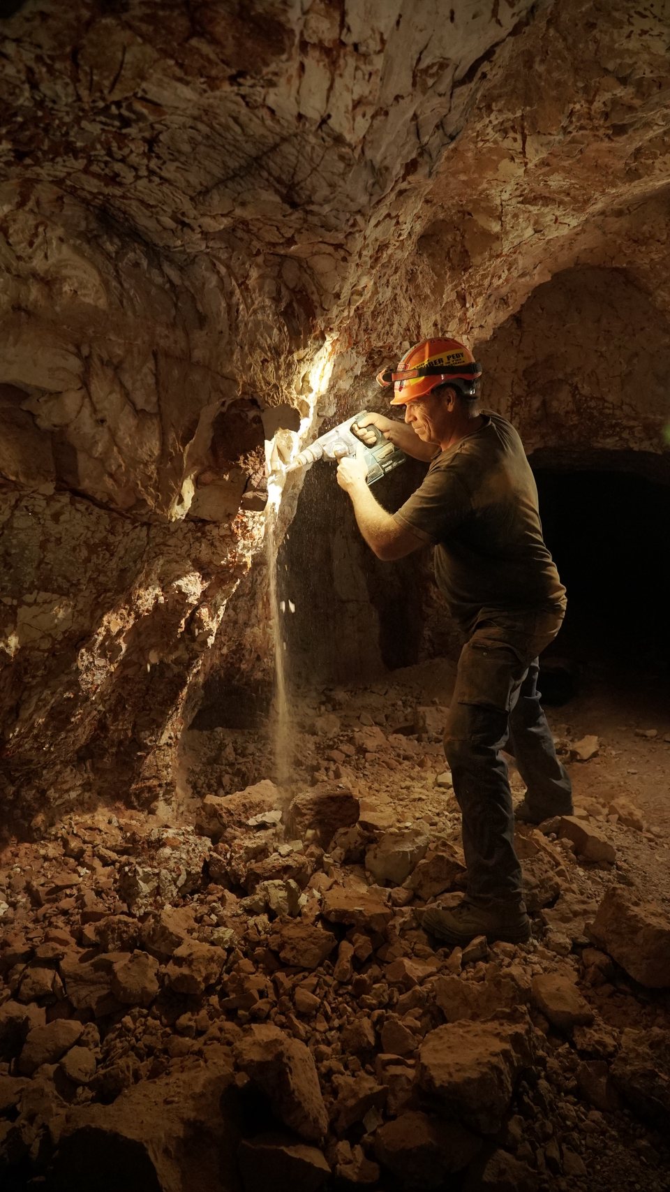 Dan driving a rotary hammer into an opal level underground.