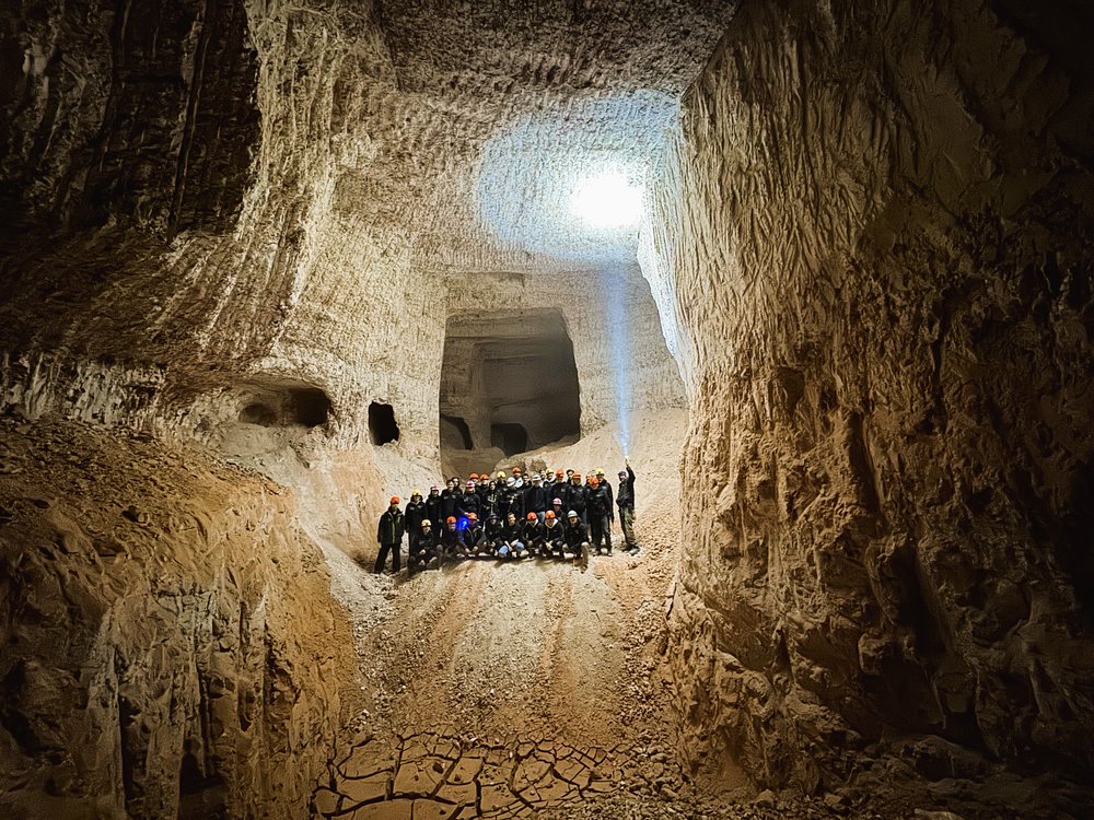 A tour group dwarfed by the walls of a large underground chamber.